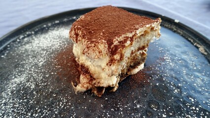 A portion of tiramisu, a traditional Italian dessert, just placed on the plate.