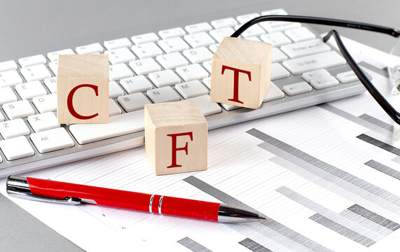 CFT written on a wooden cube on the keyboard with chart on grey background