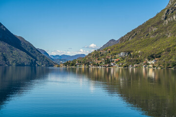 Fototapeta na wymiar Lake Lugano surrounded by mountains and a small marina with moored boats on a sunny day
