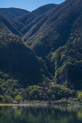 Lake Lugano surrounded by mountains and a small marina with moored boats on a sunny day