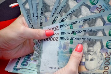 Closeup of female hands holding and counting many Armenian 20000 dram bills - obrazy, fototapety, plakaty
