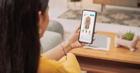 Over the Shoulder Indian Girl Using SmartphoneTo Buy a Stylish Coat: Female Browsing through Internet, Doing Online Shopping, Comparing Prices for Items on Sale on a Retail E-Commerce Website © Kitreel