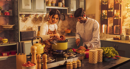 Playful Indian Couple Preparing Food in the Kitchen: Learning New Recipes, Laughing and Having Fun While Cooking. Strengthening Their Relationship Through Shared Experiences. Medium Close-up Shot