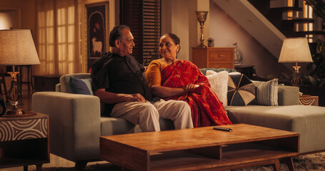 Fototapeta premium Blessed Love: Elderly Couple Enjoying a Quiet Evening at Home, Talking and Communicating. Beautiful Indian Husband and Wife Recalling Memories Together in Cozy Living Room, Feeling Nostalgic