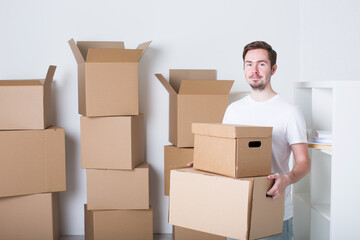 Fototapeta premium Young man in a rented apartment with boxes, concept of moving house