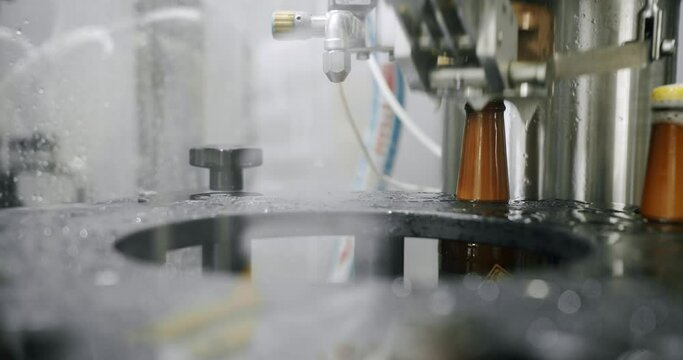 Bottles of brown beer in a factory moving along the conveyor belt. Beer bottles are filled with automatic beer. Modern technology in a factory. Factory, beer concept.
