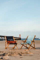 Closeup shot of two beach chairs on the sandy beach with a lighthouse in the background