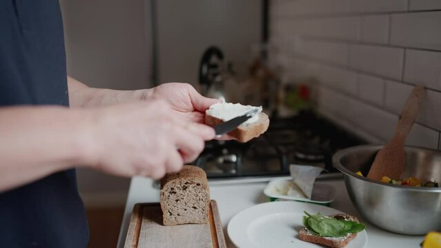Close-up of male spreading cottage cheese on bread while making breakfast