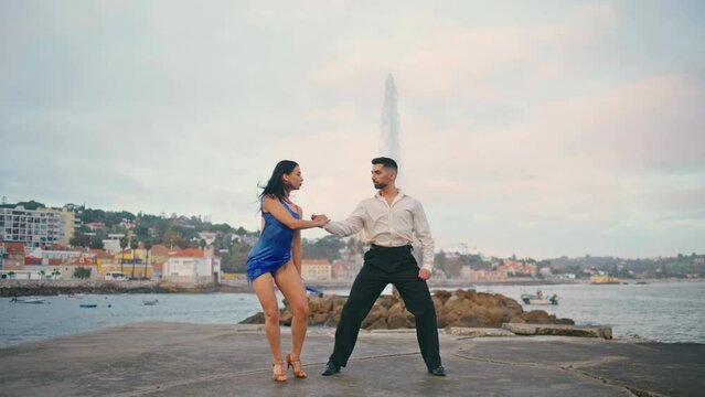 Hot tango dancers moving seductively on gloomy waterfront. Sexy partners dancing