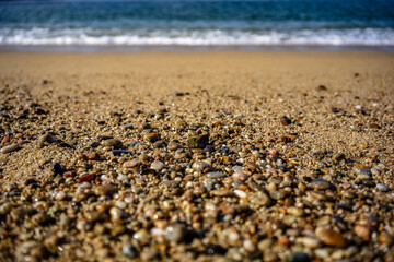Fototapeta na wymiar Closeup shot of a rocky and sandy beach with turquoise sea waves in the background
