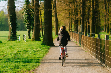 Portrait of young attractive woman riding on bicycle in the park in springtime.