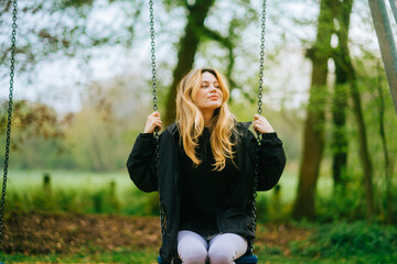 Joyful and youthful woman on a swing at the park. Concept pf people and no limit age to play and...