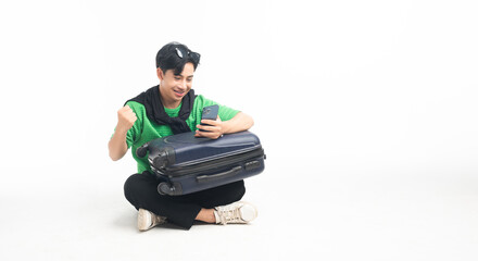 Portrait of a happy traveler young man sitting on the floor isolated on white background with phone reading text message