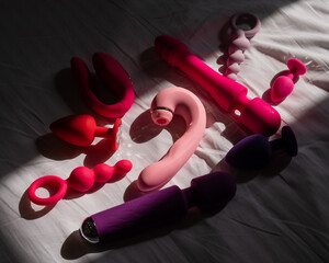A set of sex toys on a white sheet. Personal collection of dildos.