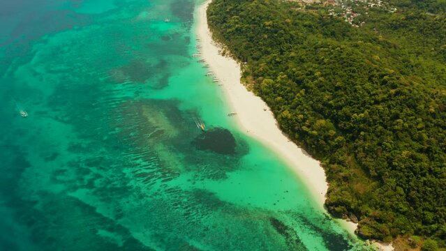 Tropical white sand beach, near the blue lagoon and corall reef from above, Boracay, Philippines. Sandy beach with tourists. Summer and travel vacation concept.