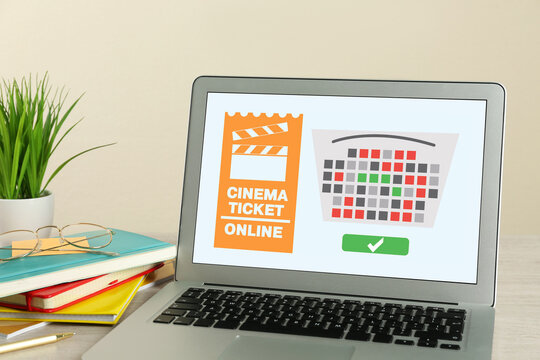 Buying cinema tickets online. Laptop with open website or application on table