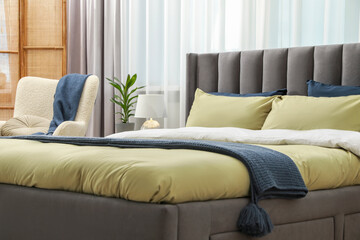 Comfortable bed with cushions and bedding in room. Stylish interior