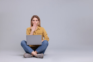 Emotional woman with laptop on light grey background. Space for text