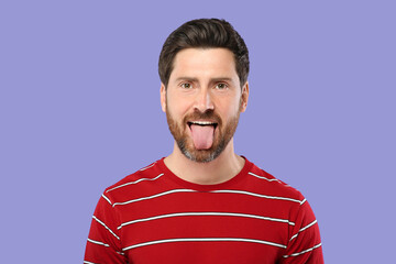 Man showing his tongue on violet background