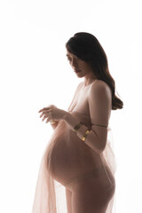 charming and graceful brunette pregnant woman in golden bracelets and delicate chiffon draping...