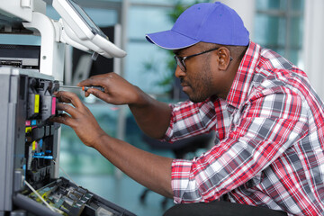 young male technician repairing digital photocopier machine