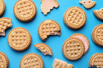 Tasty sandwich cookies with cream on light blue background, flat lay