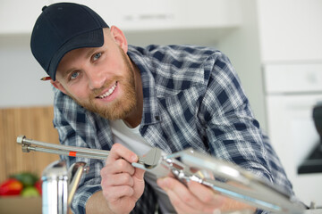 male plumber assembling metal sink hoses