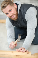 man hammering a nail in the floor