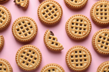 Tasty sandwich cookies with cream on pink background, flat lay