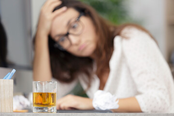 Obraz na płótnie Canvas woman very stress and drinks whiskey on workspace