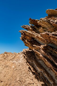 Vertical shot of rock formations against a blue sky on the coast of Korbous in Tunisia