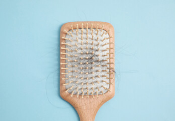 Wooden brush with lost hair on light blue background, top view