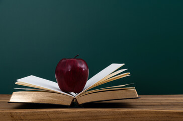 Red apple on book in front of the blackboard