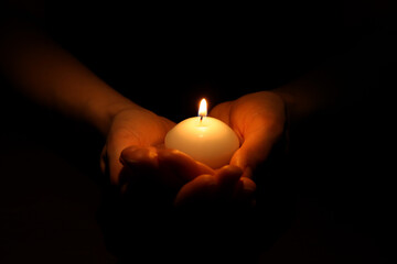 Woman holding burning candle in hands on black background, closeup - Powered by Adobe