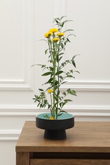 Ikebana art. Beautiful yellow flowers and green branch carrying cozy atmosphere at home