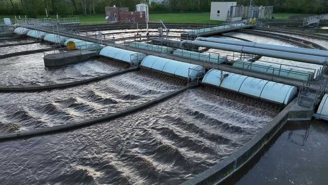 Water running through purification process at sewage treatment plant in USA. Aerial establishing shot at dusk.