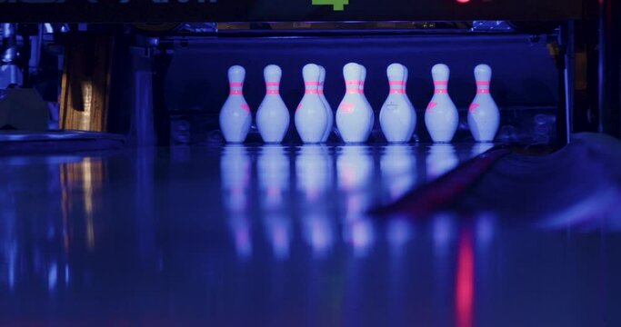 Amidst the bowling alley's lively ambiance, ten gleaming pins stood in perfect formation, ready to collide with the approaching ball.