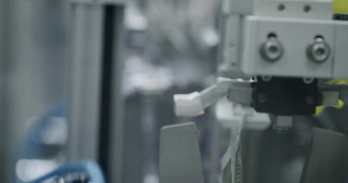 Manufacturing line at medical factory. Robotic arm put medicine package on conveyor belt. Packaged goods at automated production line. Medical factory assembly line packing medicine machine.