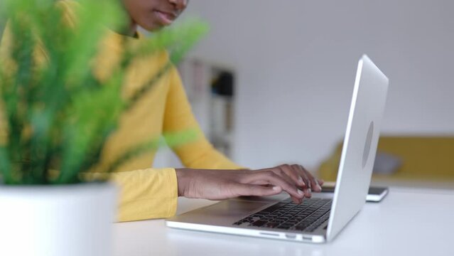 Close up view of young african woman hands working on laptop from home. Millennial female typing on computer.
