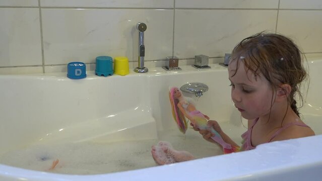 Young girl blows soap bubble offer her hand while taking bath. Slow motion.