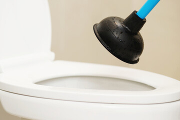 Serviceman repairing toilet with hand plunger. Clogged toilet.