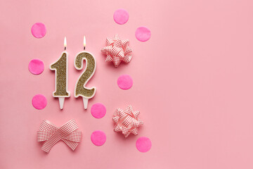 Number 12 on pastel pink background with festive decor. Happy birthday candles. The concept of celebrating a birthday, anniversary, important date, holiday. Copy space. Banner