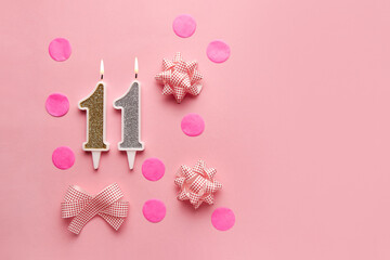 Number 11 on pastel pink background with festive decor. Happy birthday candles. The concept of...