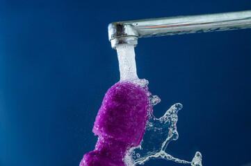 Purple vibrator under running water on a blue background. waterproof sex toy. 