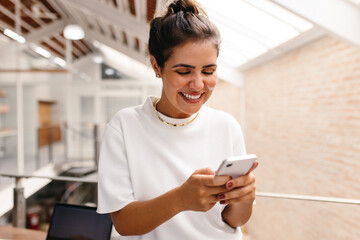 Happy young businesswoman reading a text message on her smartphone