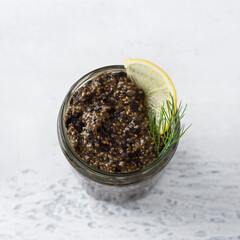 Vegan healthy chia caviar with nori and soy sauce in a jar, bread with seeds and greens on light blue background with christmas decorations, top view