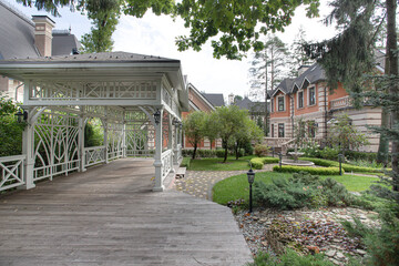view of a white wooden gazebo with a large house with a garden