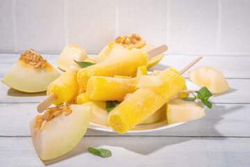 

 Melon ice cream popsicle, sweet sorbet lollypops, homemade gelato on sticks, with slices of fresh cantalupa melon and mint leaves 
