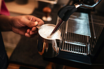 Fototapeta na wymiar Close-up of Barista hand using high-pressure steam-operated milk frother to prepare a cappuccino coffee milk