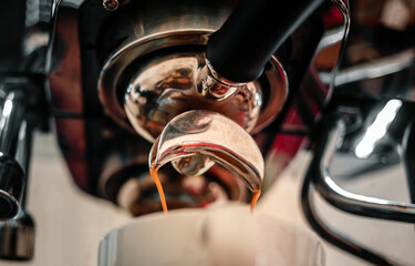 Obraz premium Close-up of espresso pouring from the coffee machine into a coffee cup. Professional coffee brewing